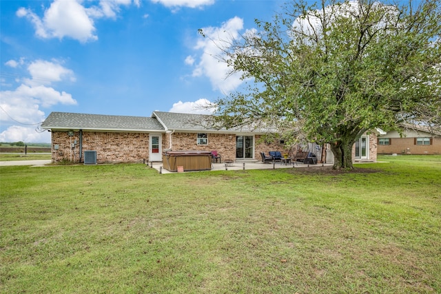 rear view of house with a yard, a hot tub, central air condition unit, and a patio area