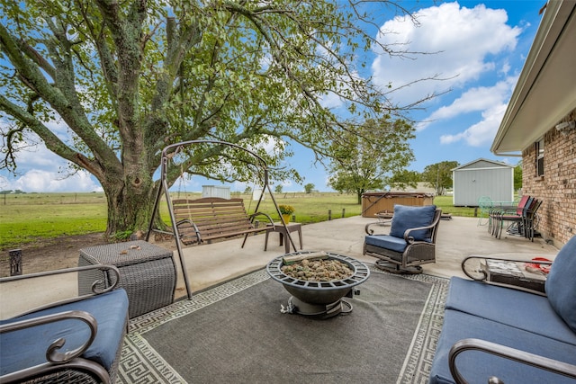 view of patio with a fire pit, a rural view, a shed, and a hot tub