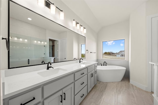 full bathroom with double vanity, a stall shower, a freestanding bath, and a sink