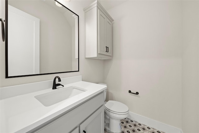 bathroom with toilet, vanity, and baseboards