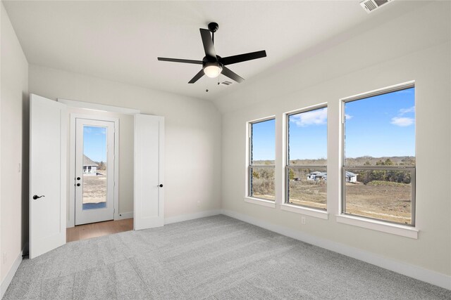 unfurnished bedroom featuring ceiling fan, light colored carpet, visible vents, baseboards, and vaulted ceiling