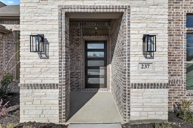 property entrance featuring a shingled roof and brick siding