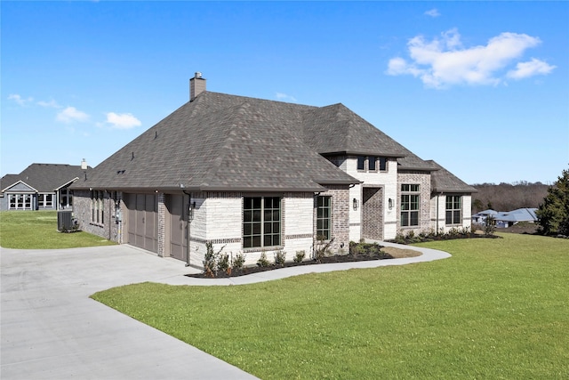 view of front of property with a garage, central AC, and a front yard