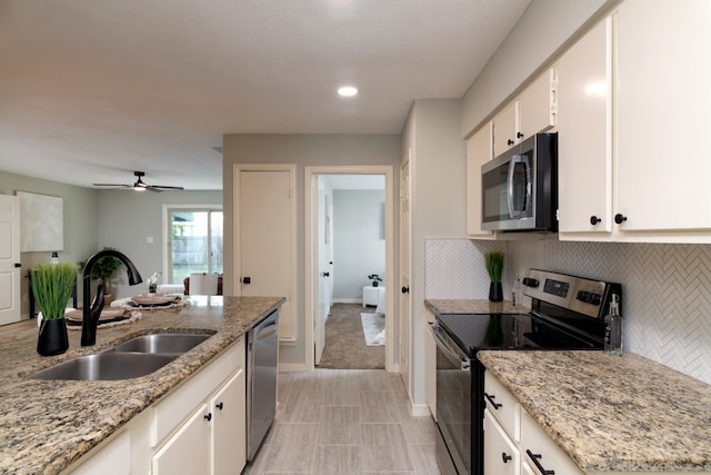 kitchen with sink, backsplash, appliances with stainless steel finishes, light stone countertops, and ceiling fan