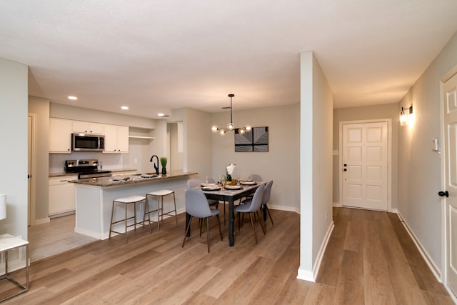 dining area with an inviting chandelier, light hardwood / wood-style flooring, and sink