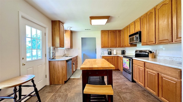 kitchen featuring decorative backsplash, a kitchen island, butcher block counters, stainless steel appliances, and sink