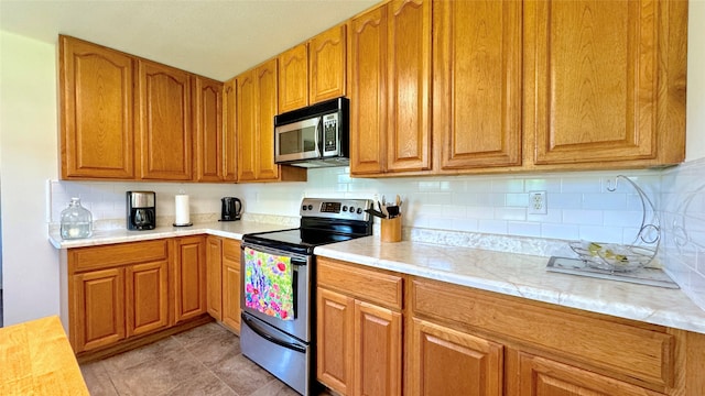 kitchen with stainless steel appliances, light tile patterned floors, and tasteful backsplash