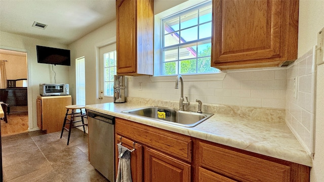 kitchen featuring light tile patterned floors, dishwasher, sink, and tasteful backsplash