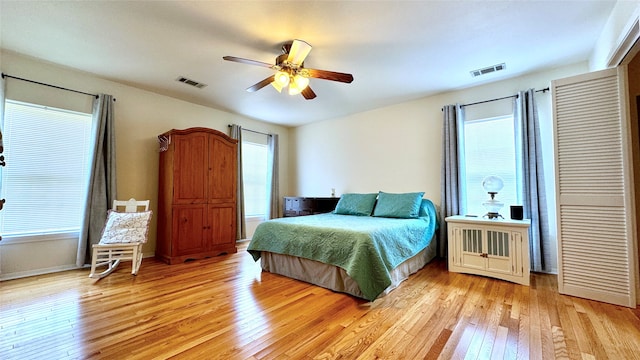 bedroom featuring multiple windows, light hardwood / wood-style floors, and ceiling fan