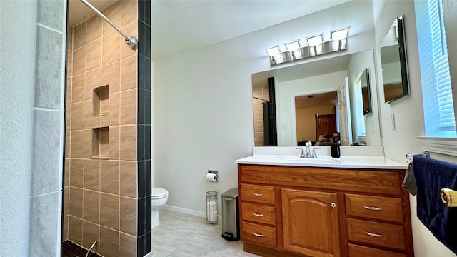 bathroom with a tile shower, vanity, and toilet