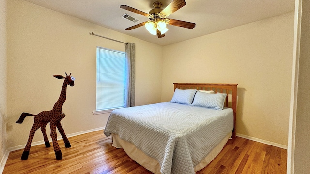 bedroom featuring multiple windows, hardwood / wood-style flooring, and ceiling fan