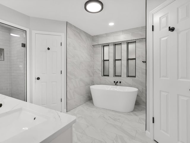 bathroom featuring vanity, independent shower and bath, and tile walls