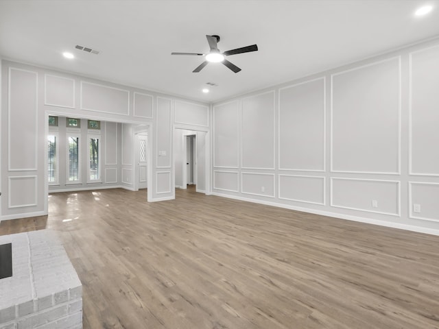 unfurnished living room featuring a brick fireplace, light hardwood / wood-style flooring, and ceiling fan