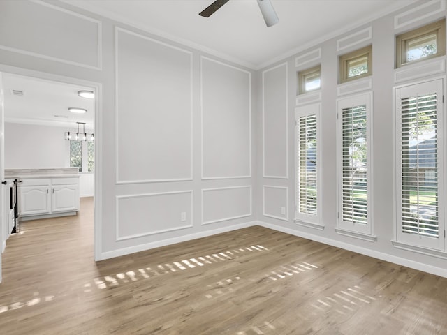 spare room featuring light hardwood / wood-style flooring, ceiling fan with notable chandelier, and ornamental molding