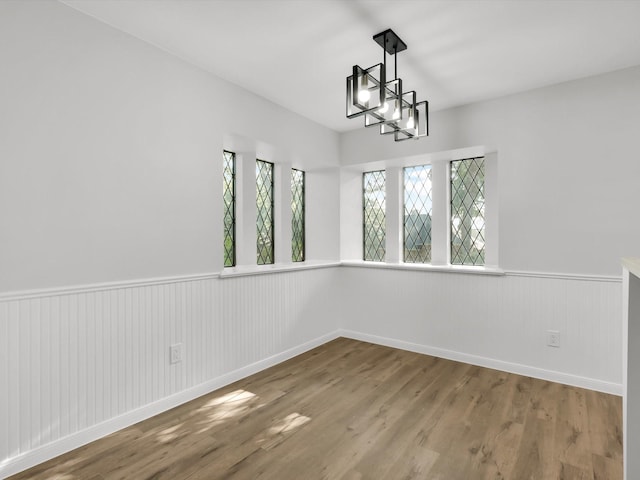 unfurnished room with wood-type flooring and a notable chandelier