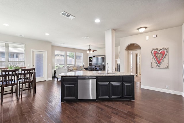1104 Dove Haven Dr, Mansfield, TX 76063 - kitchen featuring arched walkways, stainless steel dishwasher, a sink, open floor plan, and dark cabinetry