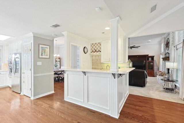 kitchen with kitchen peninsula, white cabinetry, ceiling fan, and stainless steel refrigerator