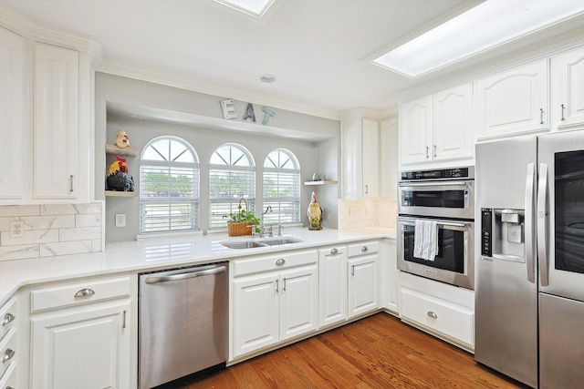 kitchen with dark wood-type flooring, tasteful backsplash, white cabinets, stainless steel appliances, and sink