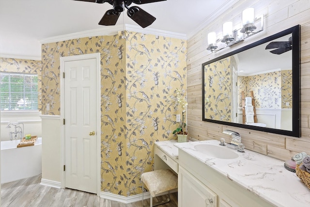 bathroom featuring wood-type flooring, a bath, ornamental molding, ceiling fan, and vanity