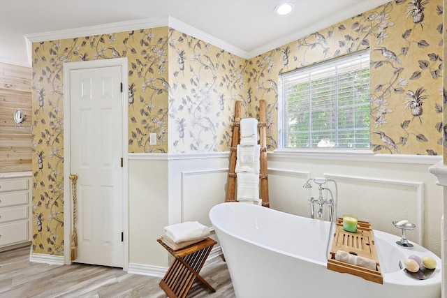 bathroom with wood-type flooring, a tub to relax in, and crown molding