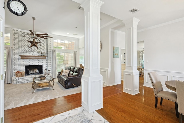 living room featuring light wood-type flooring, a fireplace, and ornate columns