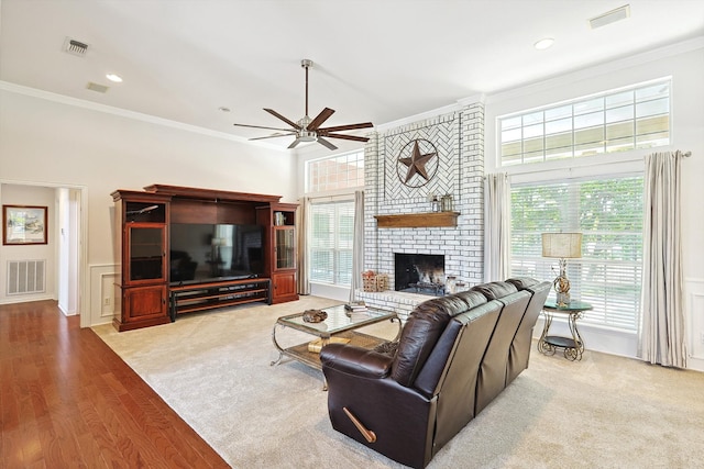 living room featuring ornamental molding, hardwood / wood-style floors, ceiling fan, and a brick fireplace