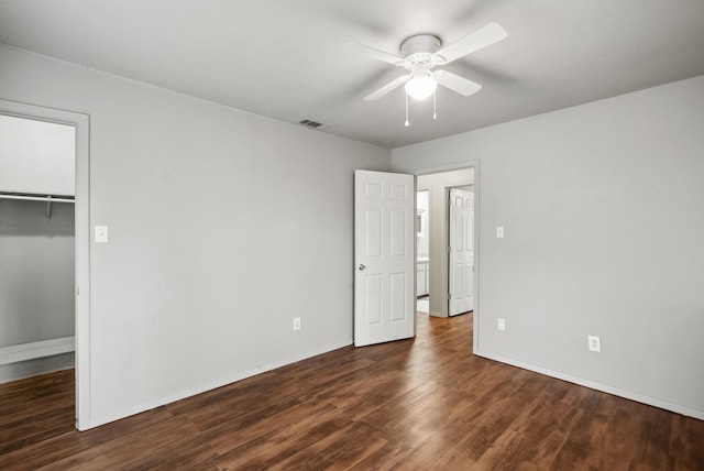 unfurnished bedroom featuring dark hardwood / wood-style flooring, a walk in closet, a closet, and ceiling fan