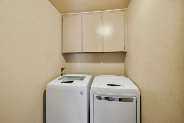 clothes washing area featuring cabinets and independent washer and dryer