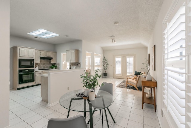 dining area featuring sink, a textured ceiling, and light tile patterned flooring