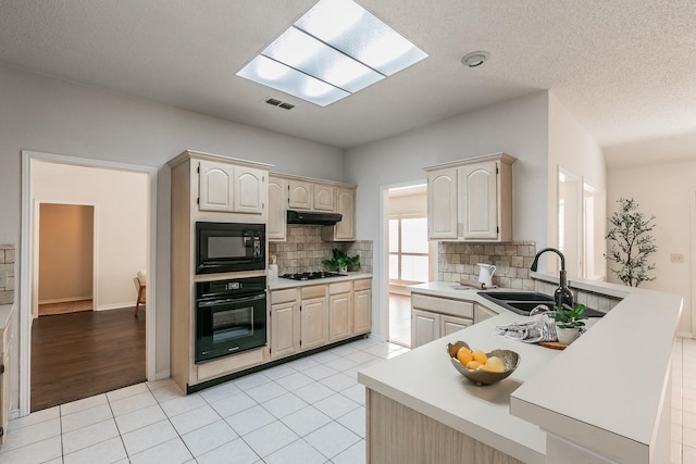 kitchen with sink, black appliances, a textured ceiling, light tile patterned floors, and backsplash