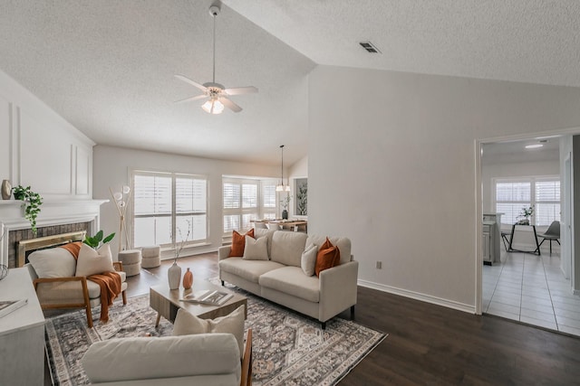 living room featuring lofted ceiling, a brick fireplace, dark hardwood / wood-style flooring, and a healthy amount of sunlight