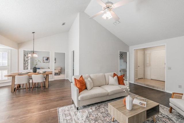 living room featuring dark wood-type flooring, ceiling fan, high vaulted ceiling, and a textured ceiling