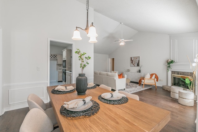 dining area with dark hardwood / wood-style flooring, ceiling fan with notable chandelier, and high vaulted ceiling