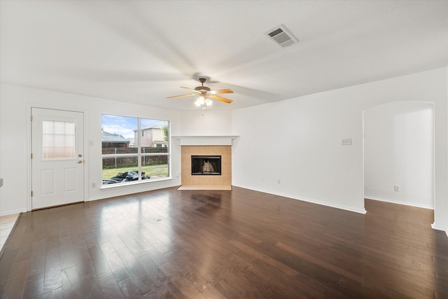 unfurnished living room featuring ceiling fan, a tile fireplace, and dark hardwood / wood-style flooring