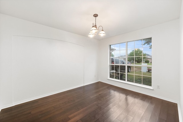 empty room featuring a chandelier and dark hardwood / wood-style flooring