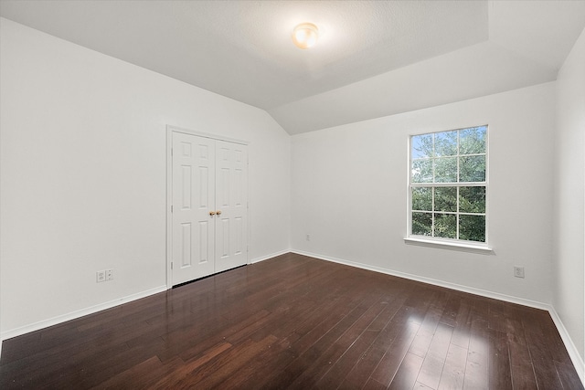 empty room featuring vaulted ceiling and dark hardwood / wood-style floors