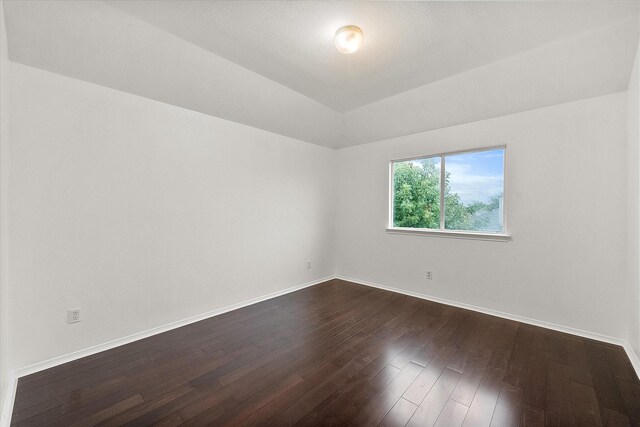 spare room with dark hardwood / wood-style floors and vaulted ceiling