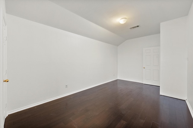 unfurnished room with vaulted ceiling and dark wood-type flooring