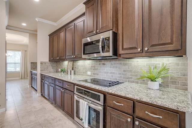 kitchen with backsplash, stainless steel appliances, light stone counters, and crown molding