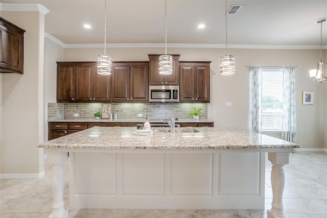 kitchen with an island with sink, light stone countertops, and a breakfast bar