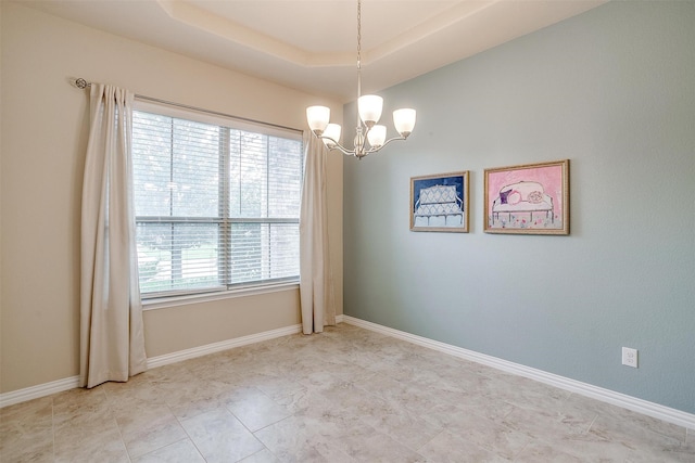 unfurnished room with a notable chandelier and a tray ceiling