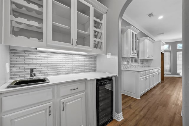 kitchen with dark hardwood / wood-style flooring, wine cooler, white cabinetry, and backsplash