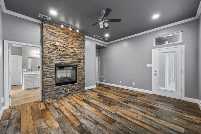 unfurnished living room featuring a fireplace, rail lighting, hardwood / wood-style floors, ornamental molding, and ceiling fan