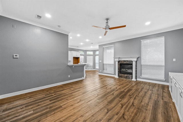 unfurnished living room with a high end fireplace, crown molding, dark hardwood / wood-style flooring, and ceiling fan