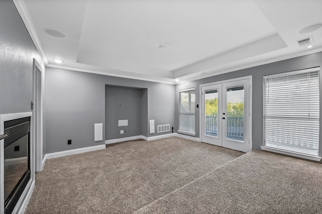 unfurnished living room with ornamental molding, carpet, a tray ceiling, and french doors