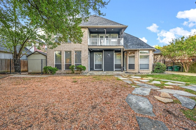 back of property featuring a storage shed and a balcony