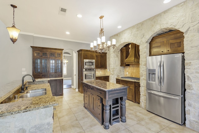 kitchen featuring appliances with stainless steel finishes, crown molding, decorative light fixtures, and custom exhaust hood