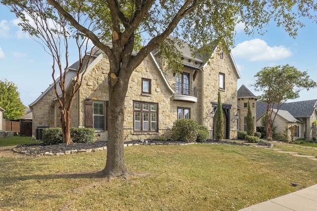 tudor home featuring a balcony and a front yard