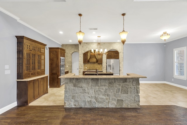 kitchen with tile patterned flooring, an island with sink, hanging light fixtures, appliances with stainless steel finishes, and ornamental molding