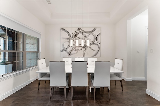 dining room with a notable chandelier, baseboards, a raised ceiling, and dark wood-type flooring